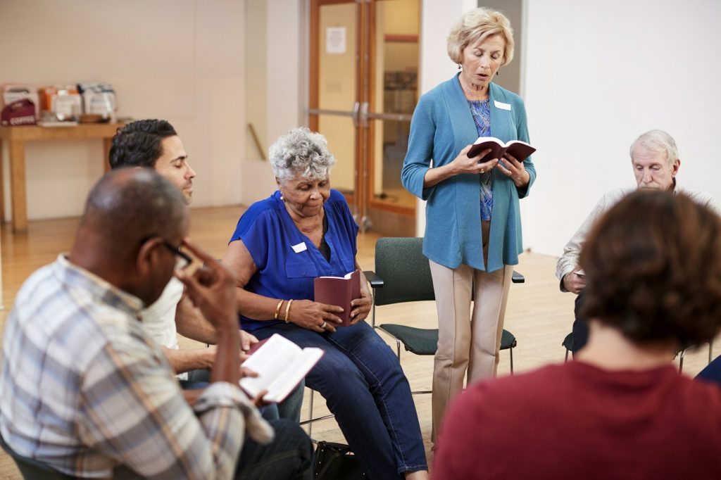 People Attending Bible Study Or Book Group Meeting In Community Center